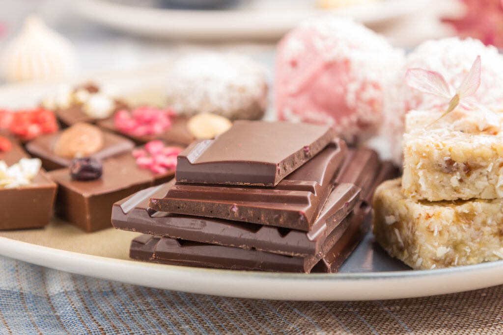 Homemade chocolate pieces and coconut candies arranged on a blue plate, with garnishes.